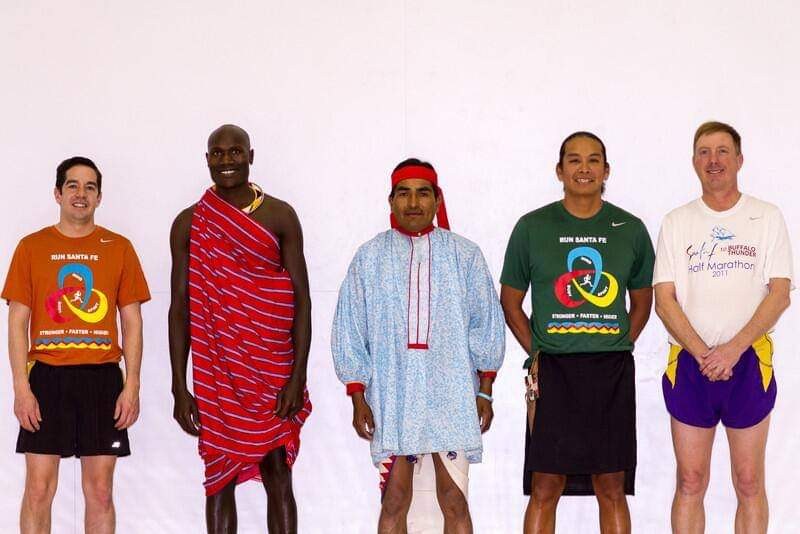 Runners in Kenyan, Ráramuri and Pueblo dress standing together with Run Santa Fe runners