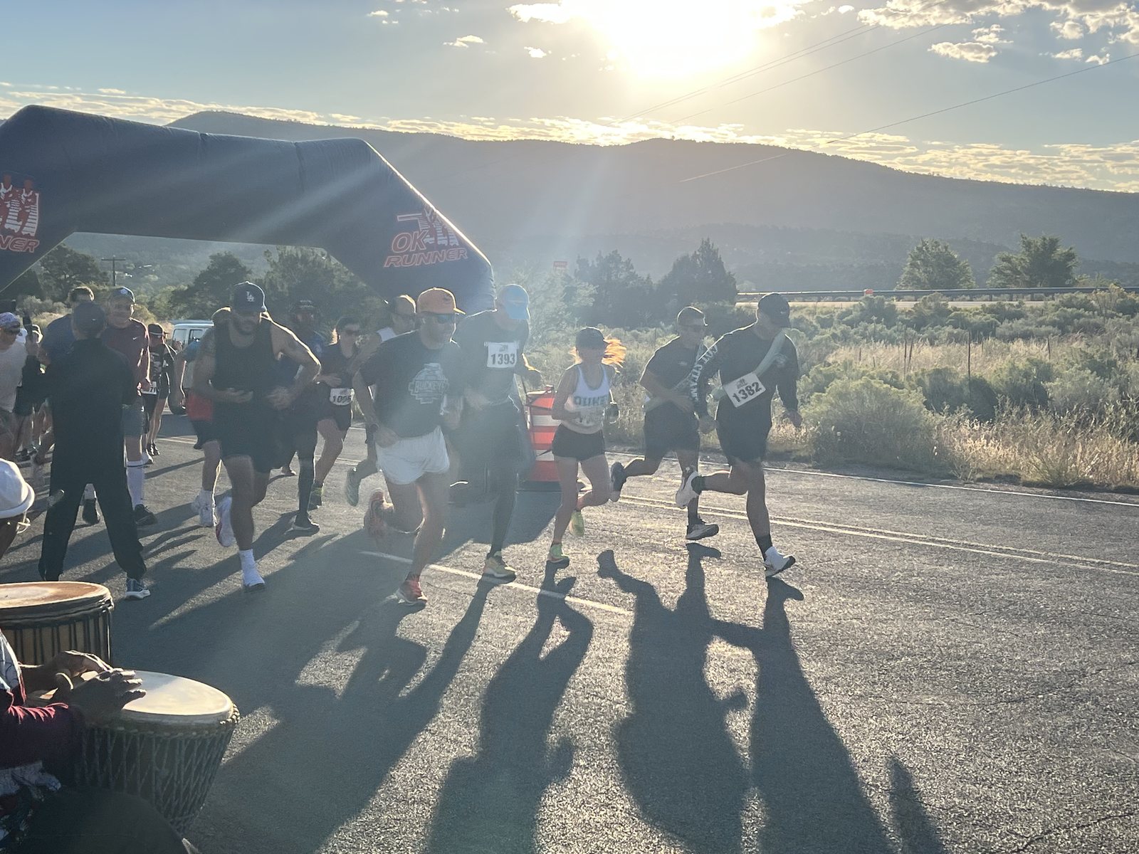 Runners set off at sunrise beneath the start arch while drummers play, Santa Fe International Half Marathon 2024