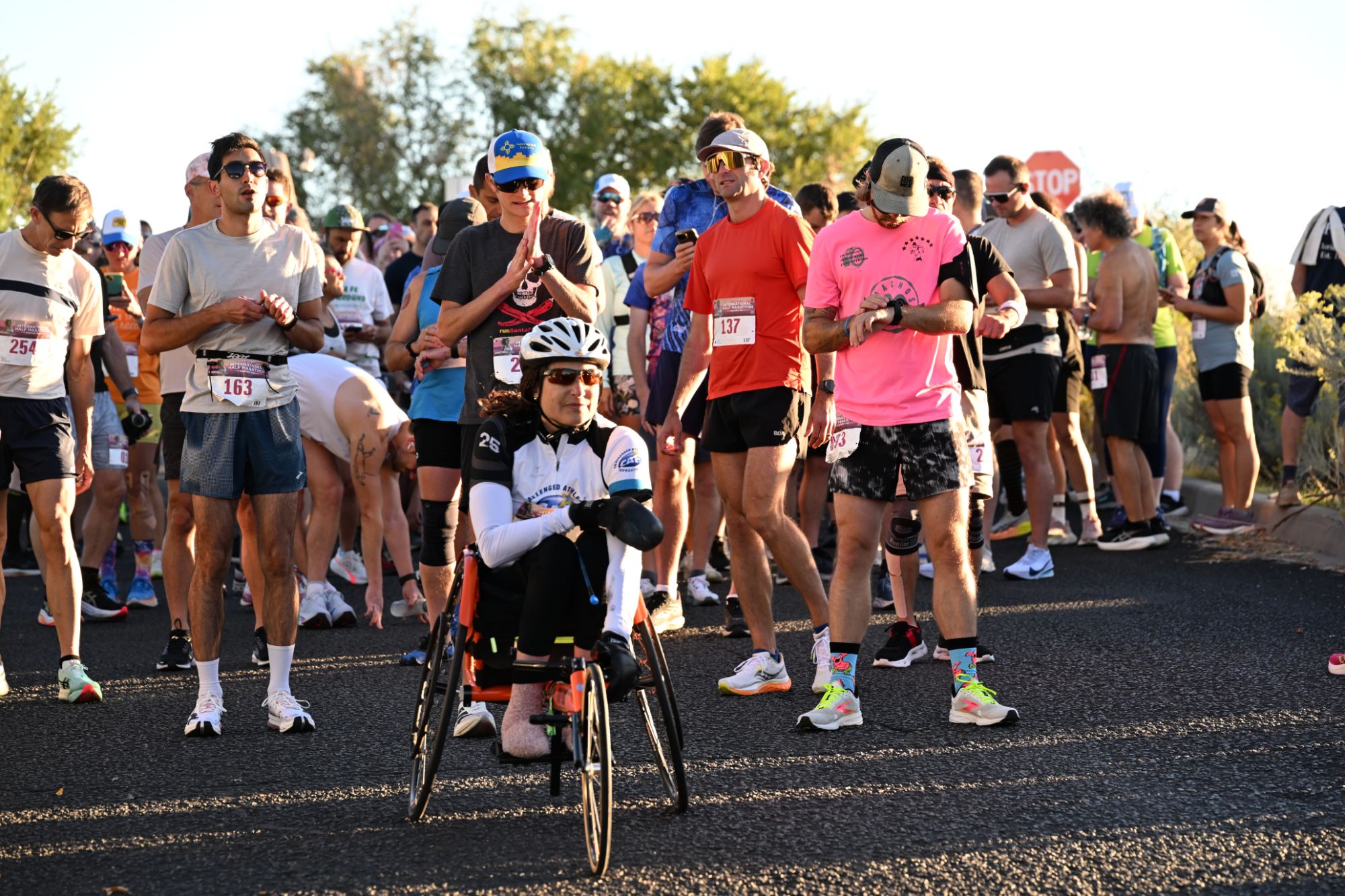 Runners gathered at the start line of the Santa Fe International Half Marathon in morning light, with a push-rim wheelchair athlete positioned at the front of the field