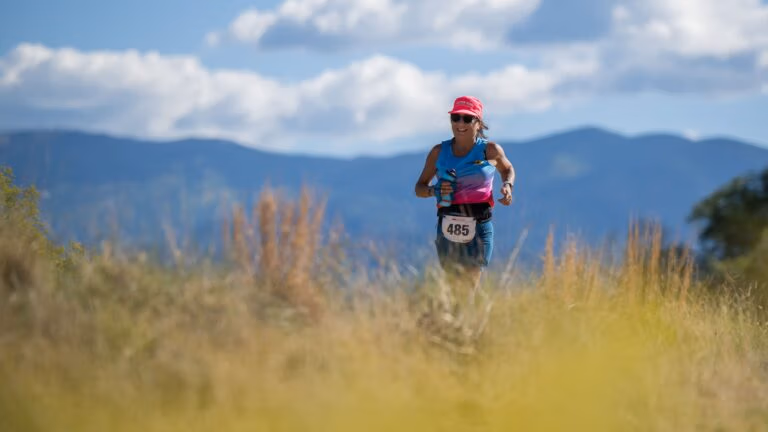 A runner passes blooming chamisa with the mountains behind