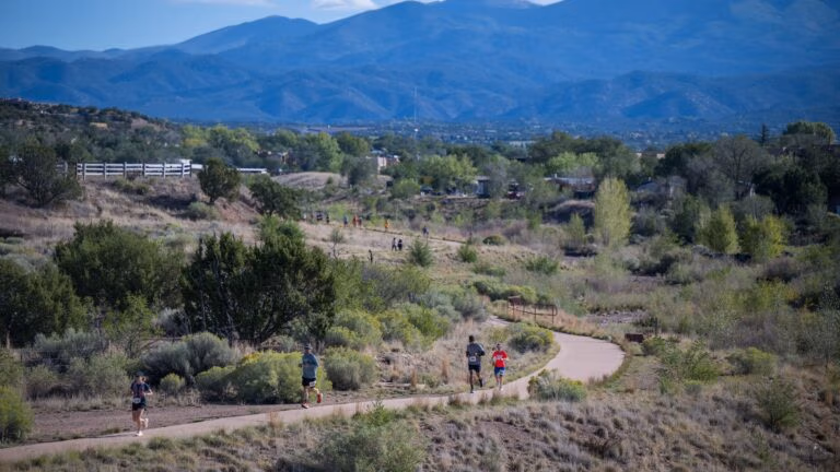 Runners wind along the Santa Fe River corridor below the Sangre de Cristo Mountains